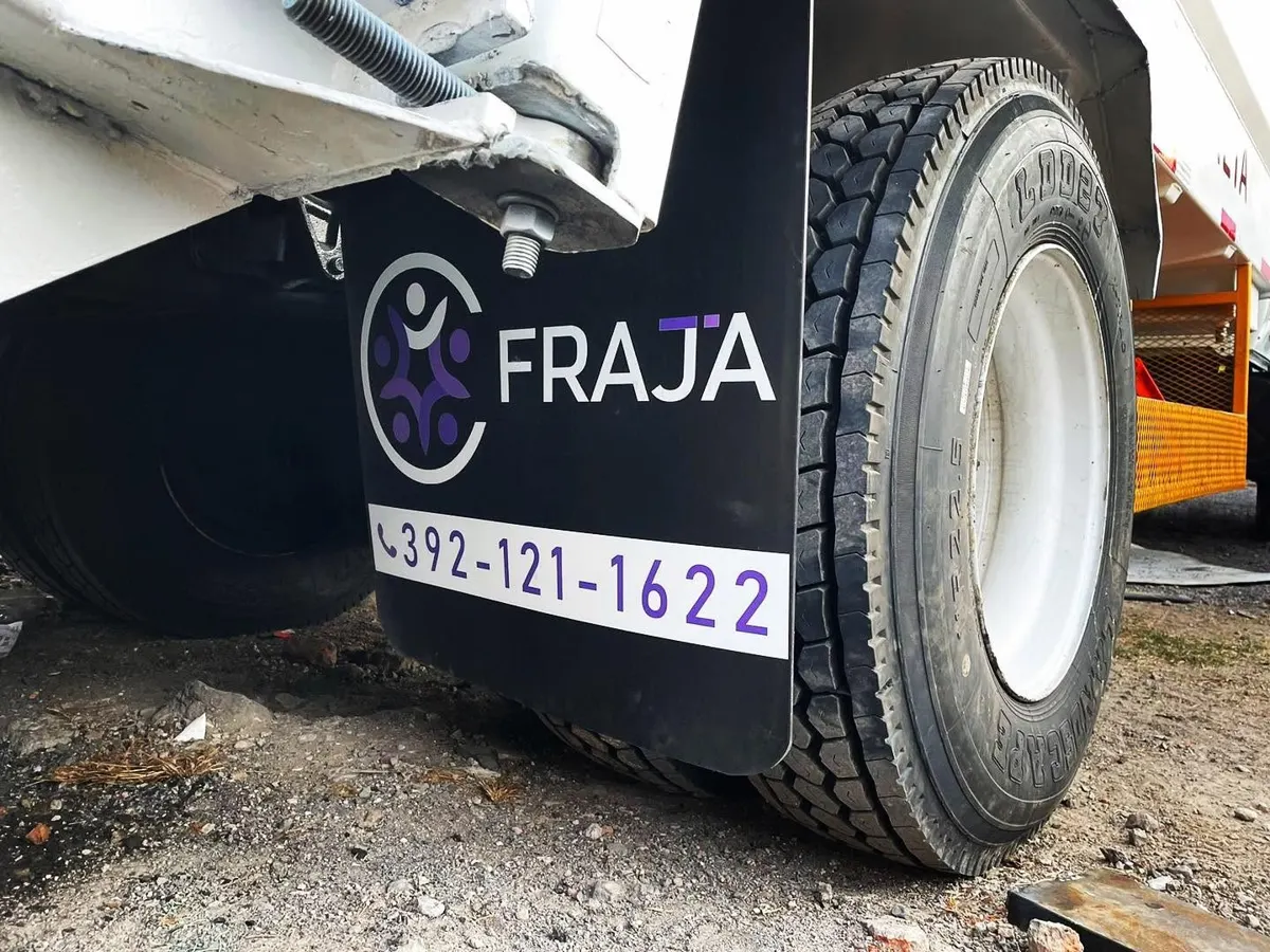 Lodera negra con logo y teléfono instalada tras la llanta