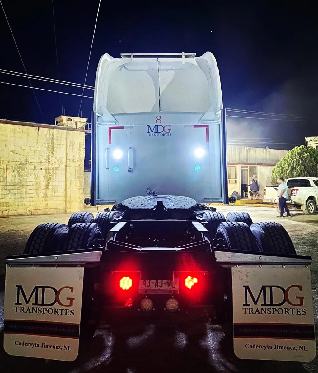Tractocamión de noche con loderas blancas personalizadas iluminadas por sus luces traseras